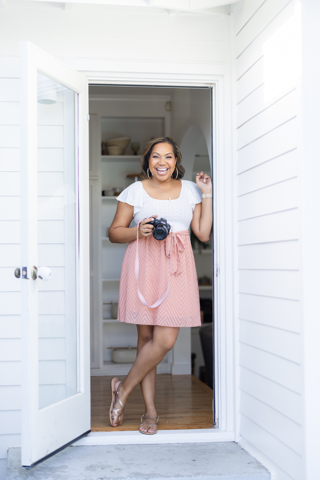 personal branding photoshoot woman standing in doorway holding a camera